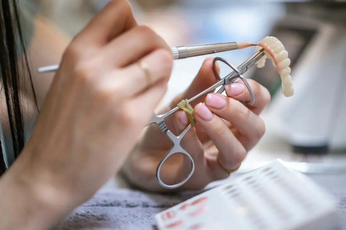 Manos de un protésico dental trabajando una prótesis